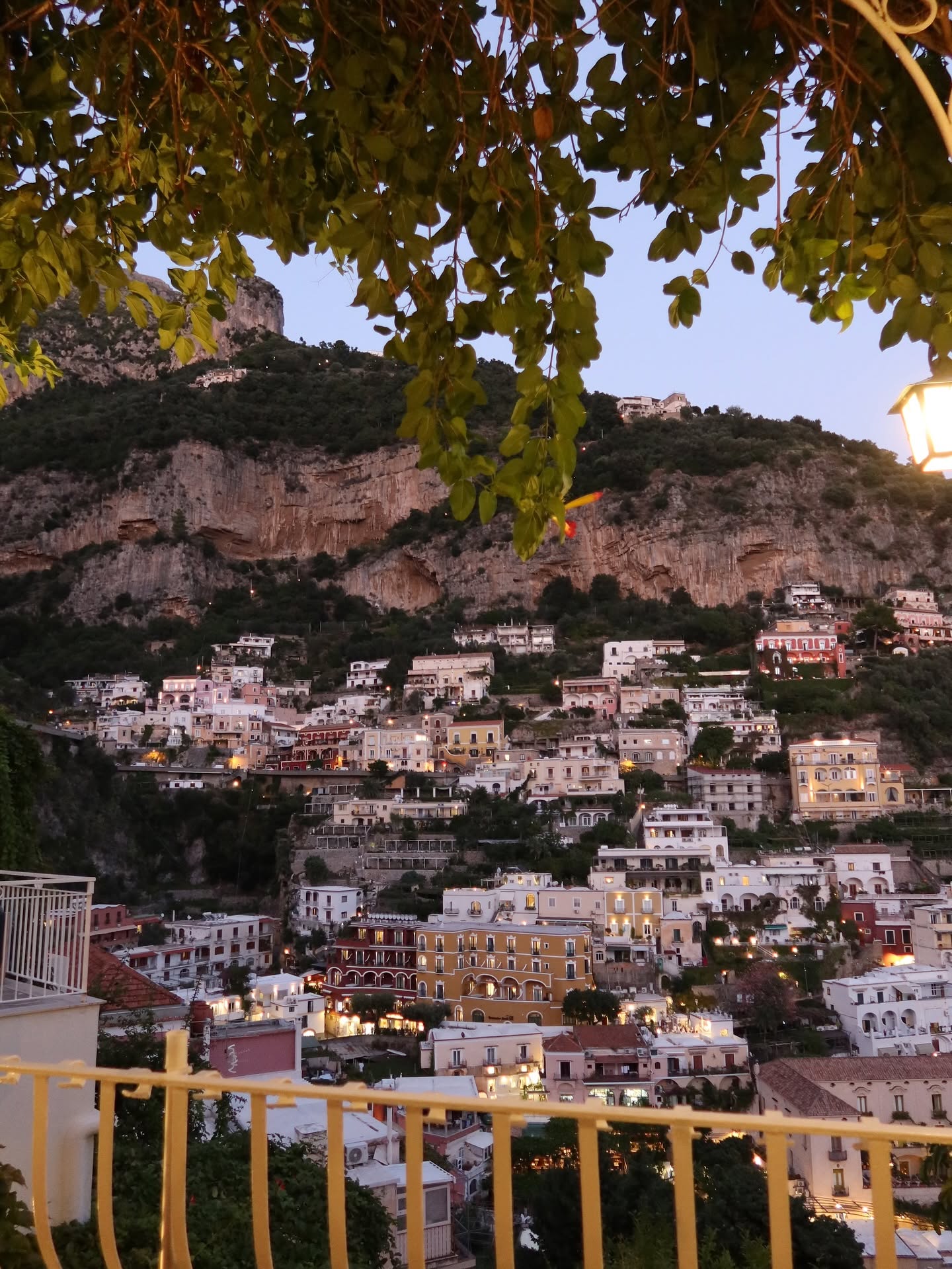 Positano lit up at dusk from a terrace above the Amalfi Coast